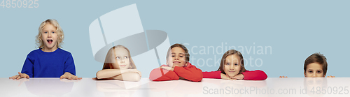 Image of Little and happy kids gesturing isolated on blue studio background. Human emotions, facial expression concept