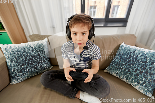 Image of boy with gamepad playing video game at home
