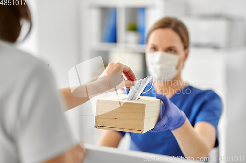 Image of doctor offering mask to patient at hospital