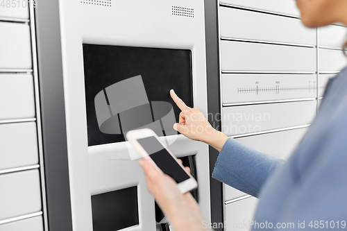 Image of woman with smartphone at automated parcel machine