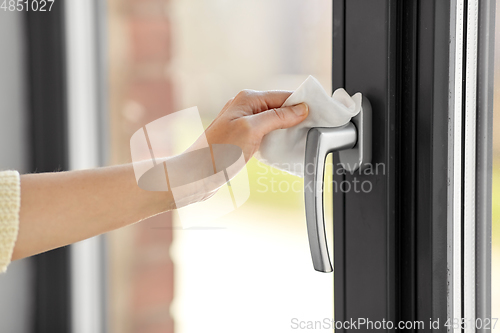 Image of woman cleaning window handle with wet wipe