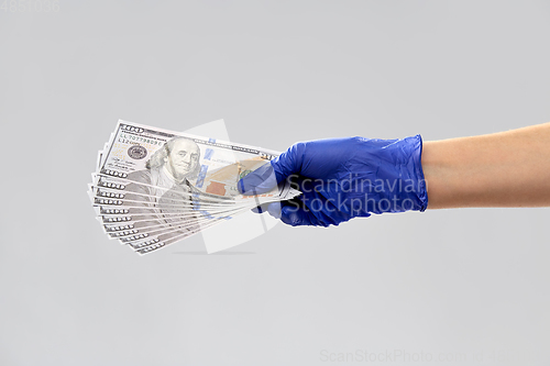 Image of close up of hand in medical glove with money