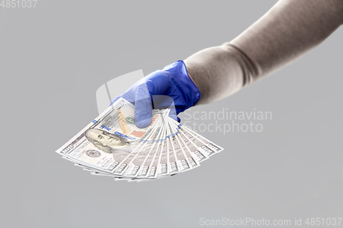 Image of close up of hand in medical glove with money