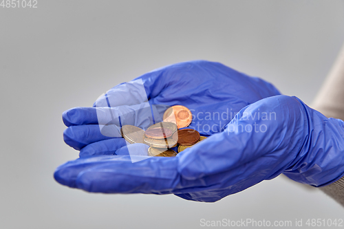 Image of close up of hands in medical gloves with money