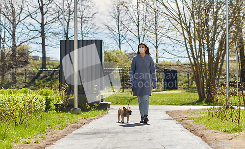 Image of woman in mask and gloves with dog walking in city