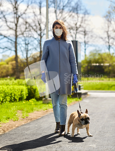 Image of woman in mask and gloves with dog walking in city