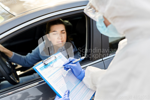 Image of healthcare worker with clipboard and woman in car