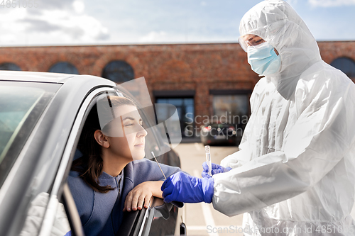 Image of healthcare worker making coronavirus test at car