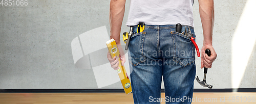 Image of man with level and working tools in pockets