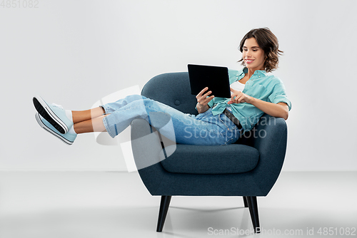 Image of happy woman with tablet pc sitting in armchair