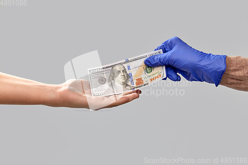 Image of close up of hand in medical glove giving money