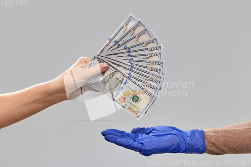 Image of close up of hand in medical glove giving money