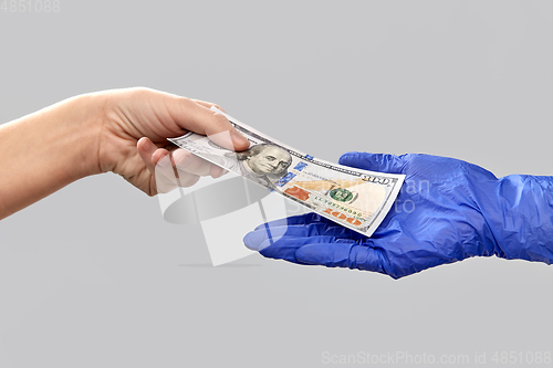 Image of close up of hand in medical glove giving money