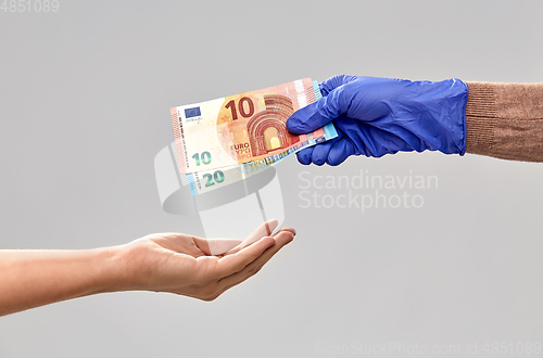 Image of close up of hand in medical glove giving money