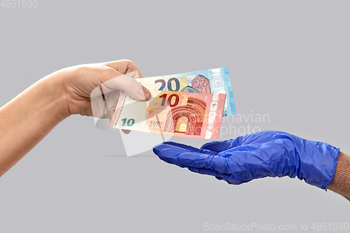 Image of close up of hand in medical glove giving money