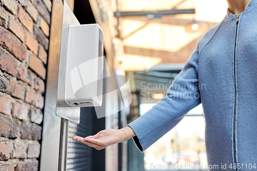 Image of close up of woman at dispenser with hand sanitizer