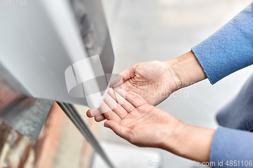 Image of close up of woman at dispenser with hand sanitizer