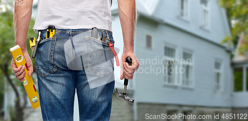Image of man with level and working tools in pockets