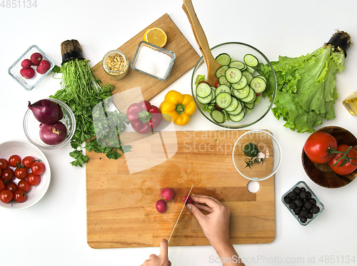 Image of hands chopping radish for salad at kitchen