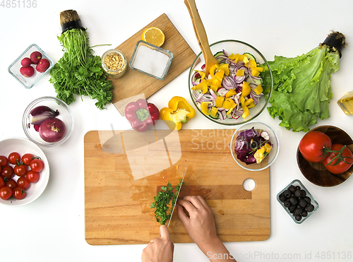 Image of hands chopping parsley for salad at kitchen