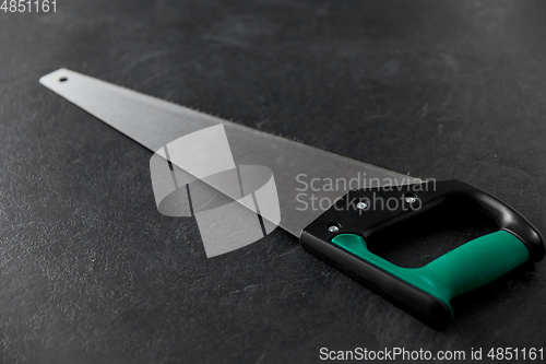 Image of saw on slate background