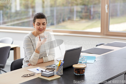 Image of woman with smartphone recording voice at office