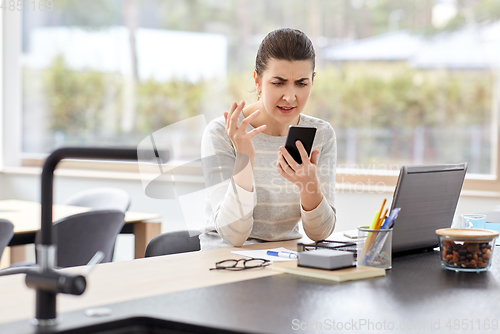 Image of angry woman calling on smartphone at home office