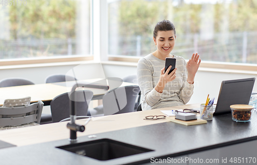 Image of woman with cellphone has video chat at home office