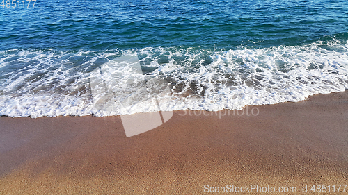 Image of Sea wave with white foam on the sandy beach