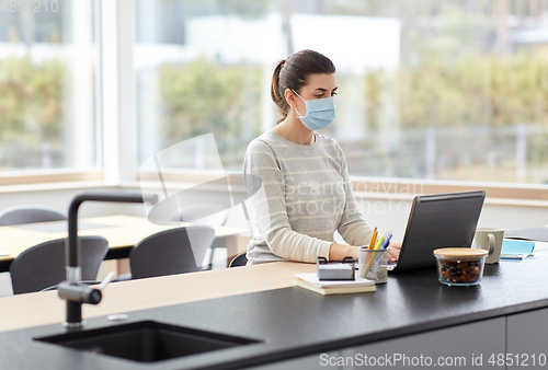 Image of woman in mask with laptop working at home office