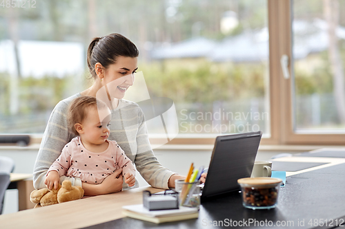 Image of mother with baby and laptop working at home office