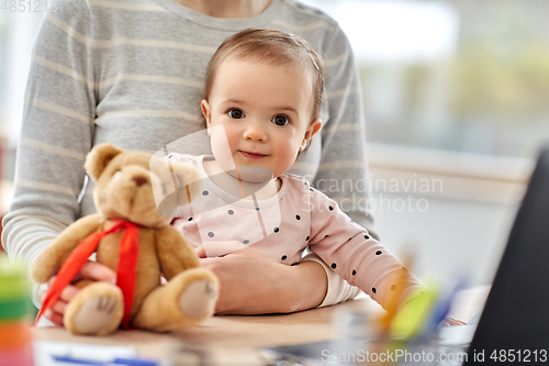 Image of happy baby with mother working at home office