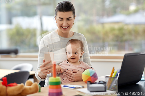 Image of mother with baby and phone working at home office