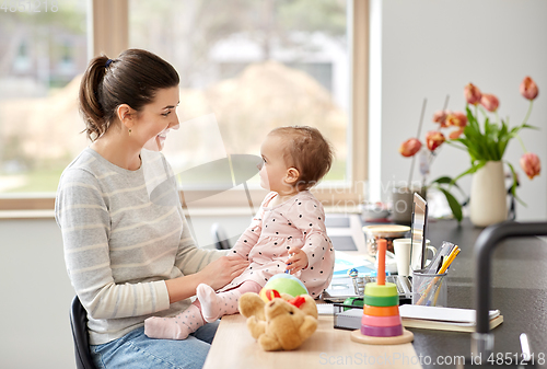 Image of happy mother with baby working at home office