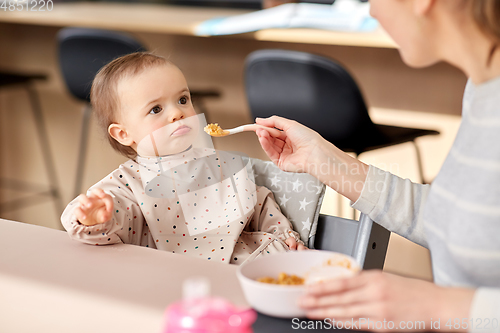 Image of happy mother feeding baby with puree at home