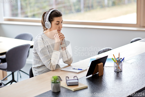 Image of woman in headphones with tablet pc working at home