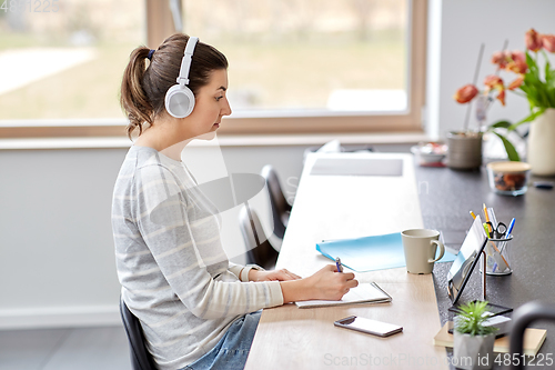 Image of woman in headphones with tablet pc working at home