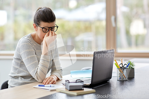 Image of tired woman with laptop working at home office