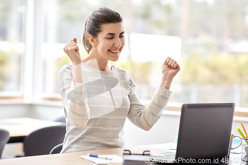 Image of happy woman with laptop working at home office