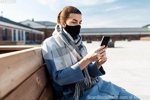 Image of woman in face mask with smartphone in city