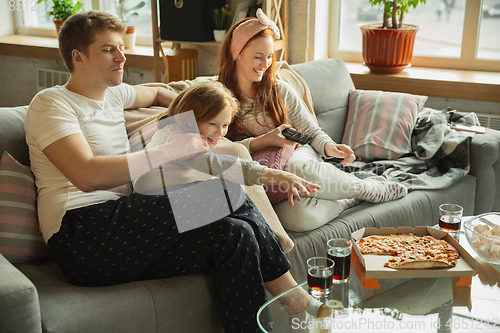 Image of Family spending nice time together at home, looks happy and cheerful, eating pizza