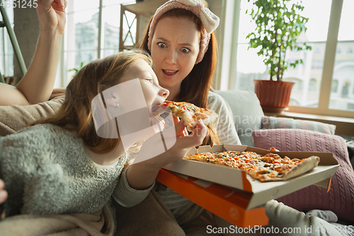 Image of Family spending nice time together at home, looks happy and cheerful, eating pizza. Close up.
