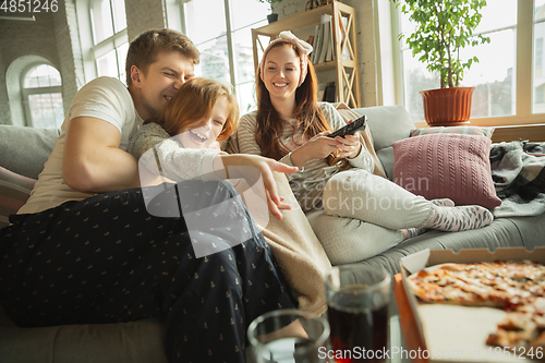 Image of Family spending nice time together at home, looks happy and cheerful, eating pizza