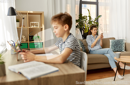 Image of mother with smartphone and son learning at home