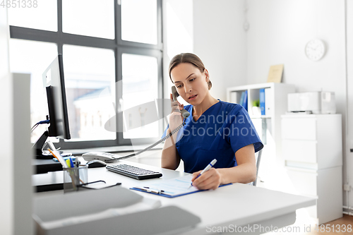 Image of doctor with computer calling on phone at hospital