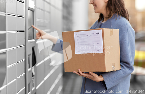 Image of smiling woman with box at automated parcel machine