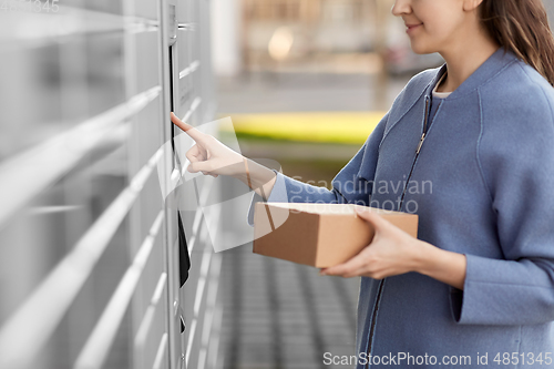 Image of smiling woman with box at automated parcel machine