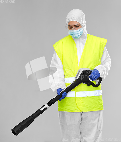 Image of sanitation worker in hazmat with pressure washer