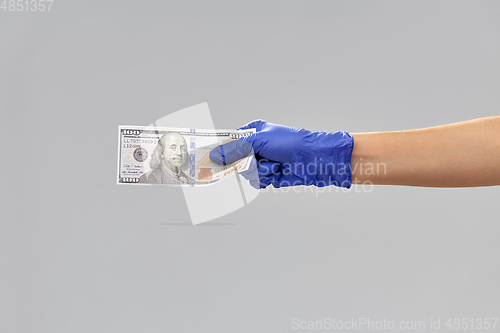 Image of close up of hand in medical glove with money