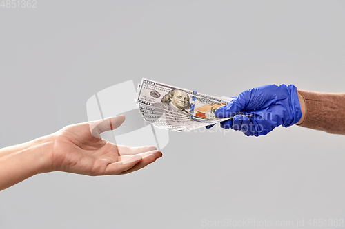 Image of close up of hand in medical glove giving money